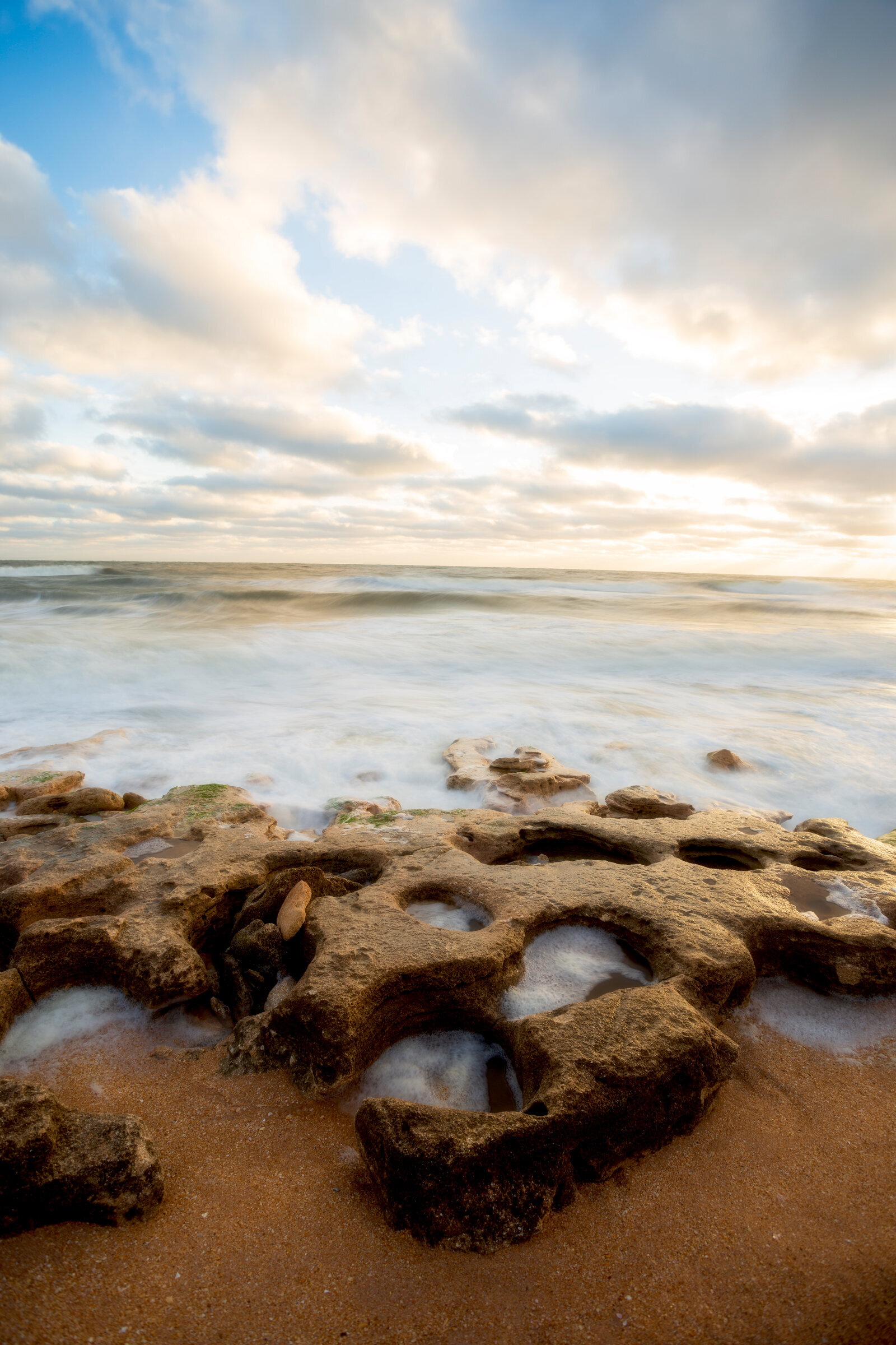 Golden rocks glowing with soft tide movement at sunset