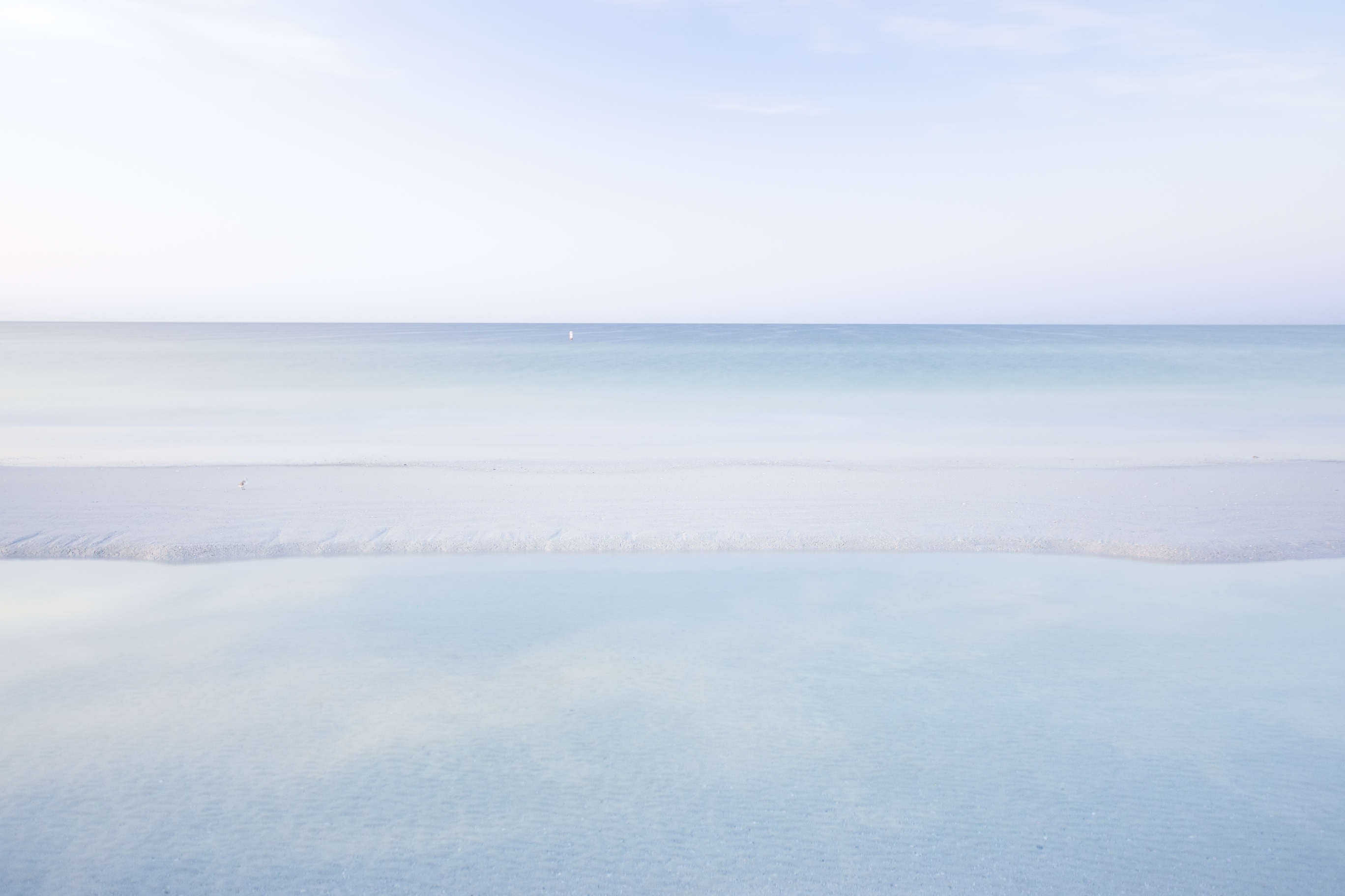Perfectly still waterline merging with the soft horizon
