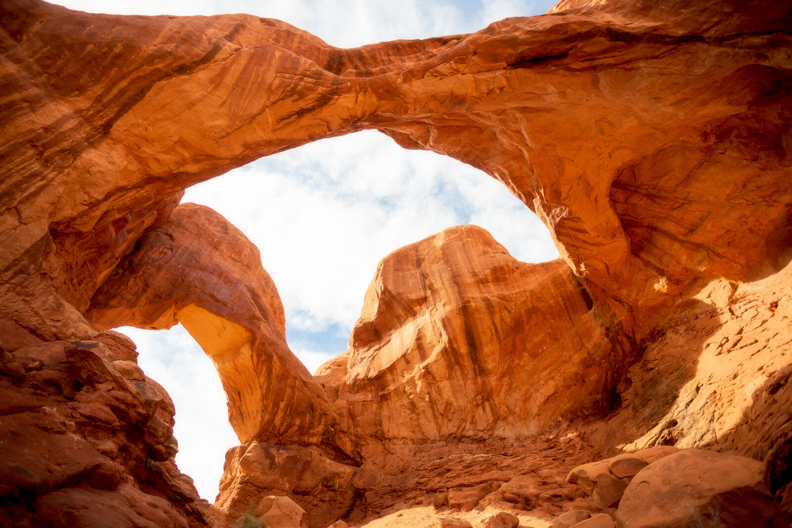 Two natural sandstone arches with warm morning light in Utah desert